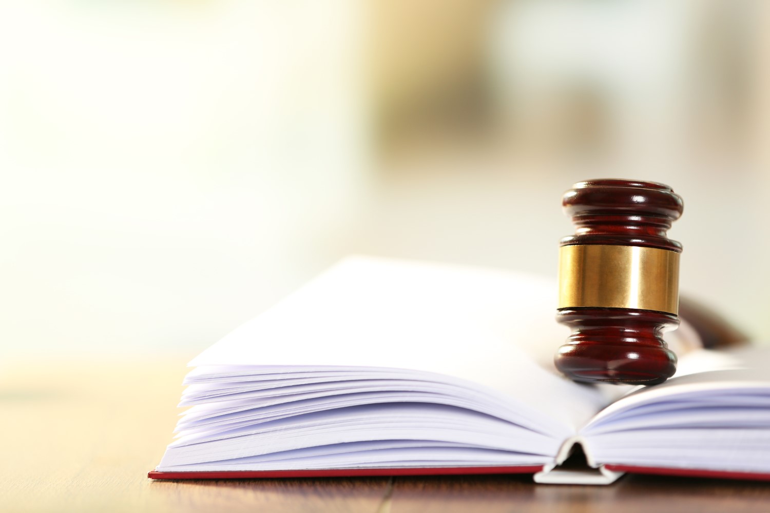 Wooden judges gavel lying on law book, close up